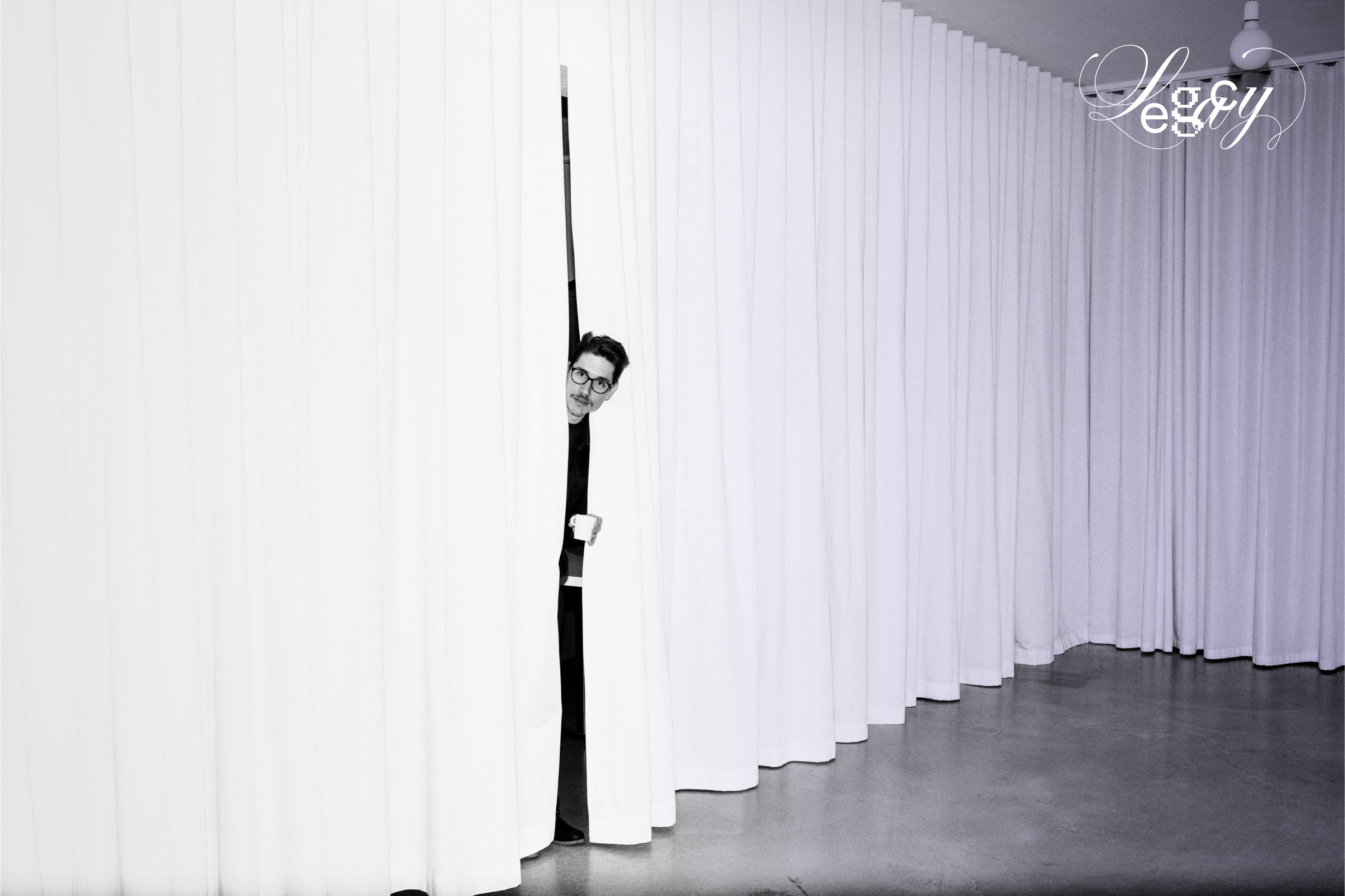 Raum mit weißem Vorhang an den Seiten, durch den Jan mit einer Kaffetasse in der Hand hervorschaut