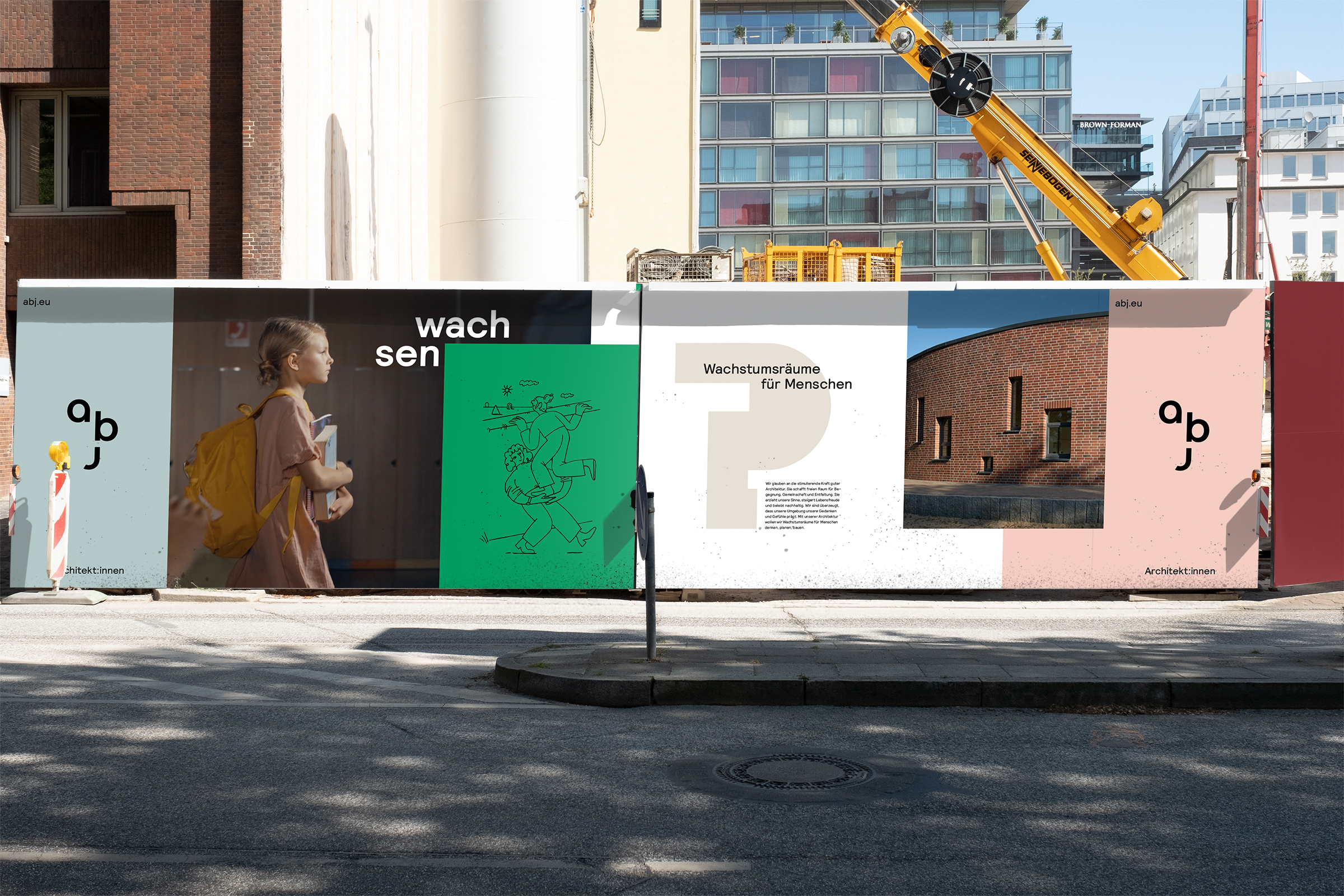 Ein Bauzaun mit Werbeplakaten von abj Architekt:innen vor einer Stadt.
