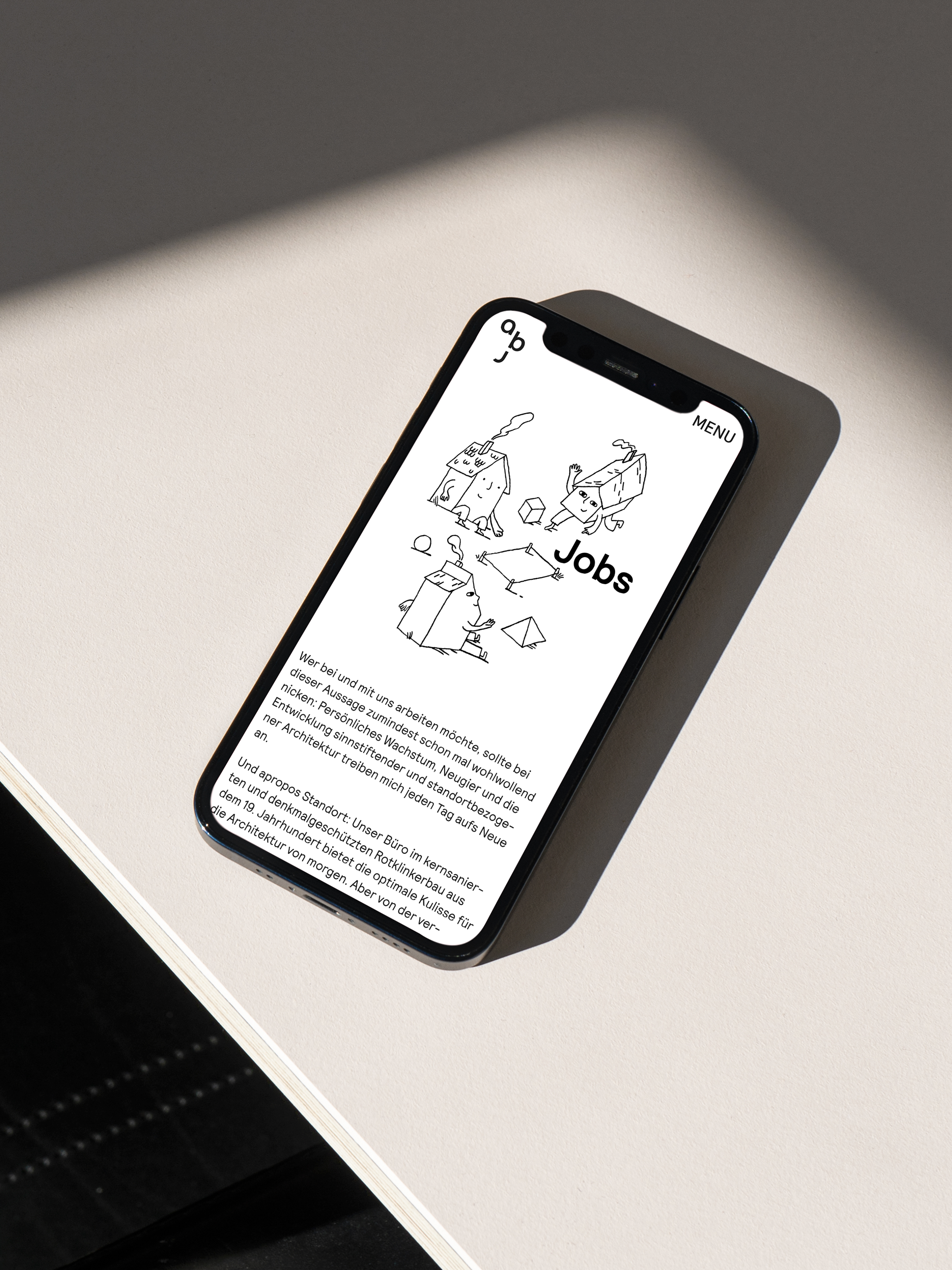 Ein Smartphone liegt auf einem weißen Tisch und zeigt eine Job-Seite der abj Website mit Illustrationen.