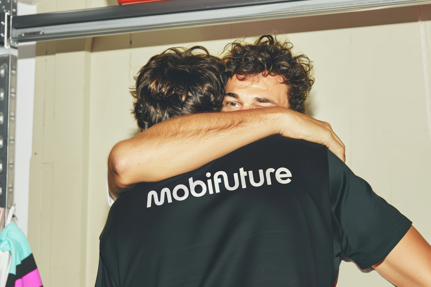 Schnappschuss des Logos der Mobifuture auf dem Rücken eines schwarzen Sportrikots von zwei Männern, die sich freundschaftlich umarmen.