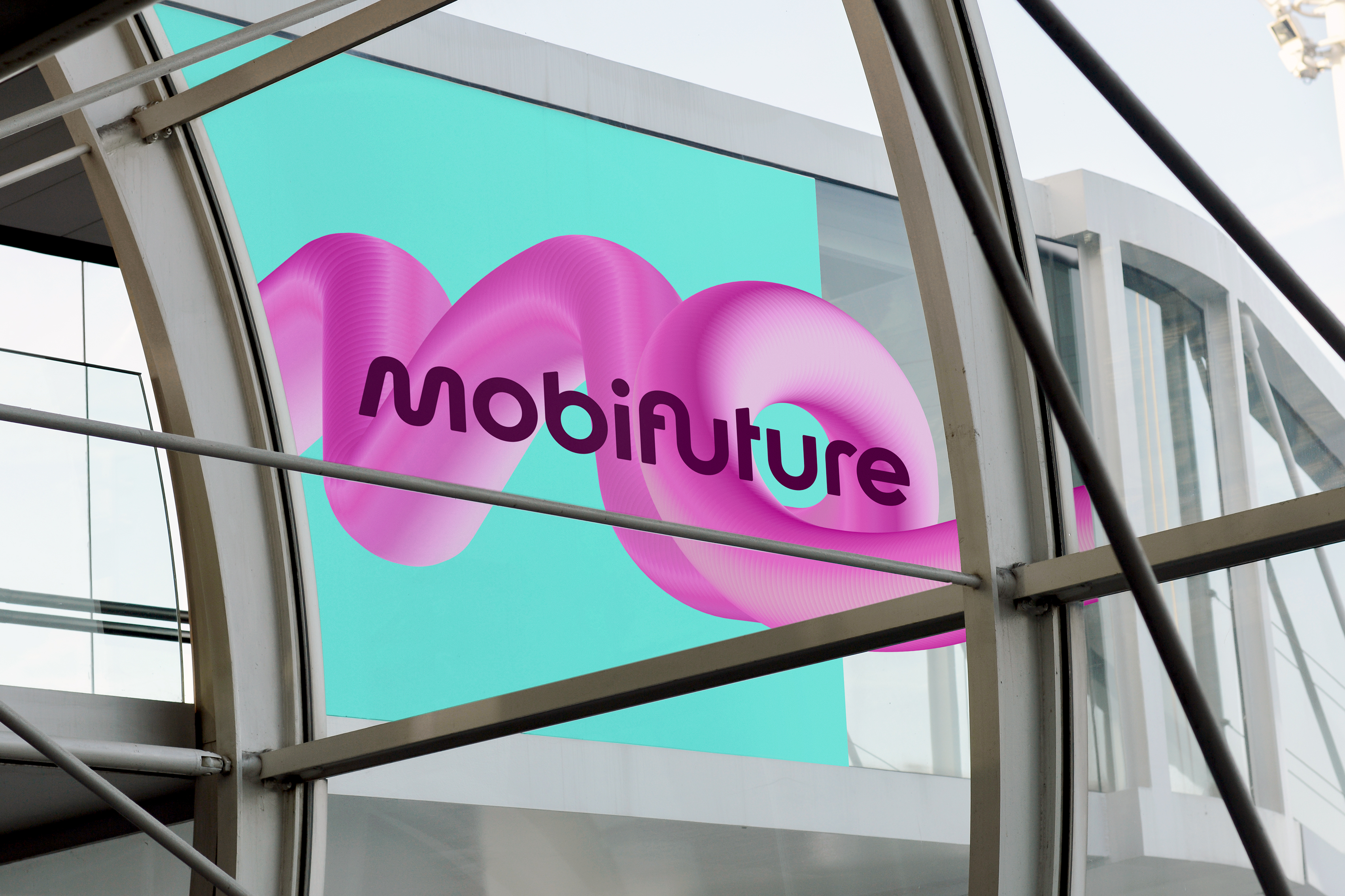 Large-scale Mobifuture key visual applied to the glass facade of a trade fair building, visible through an opposite window.