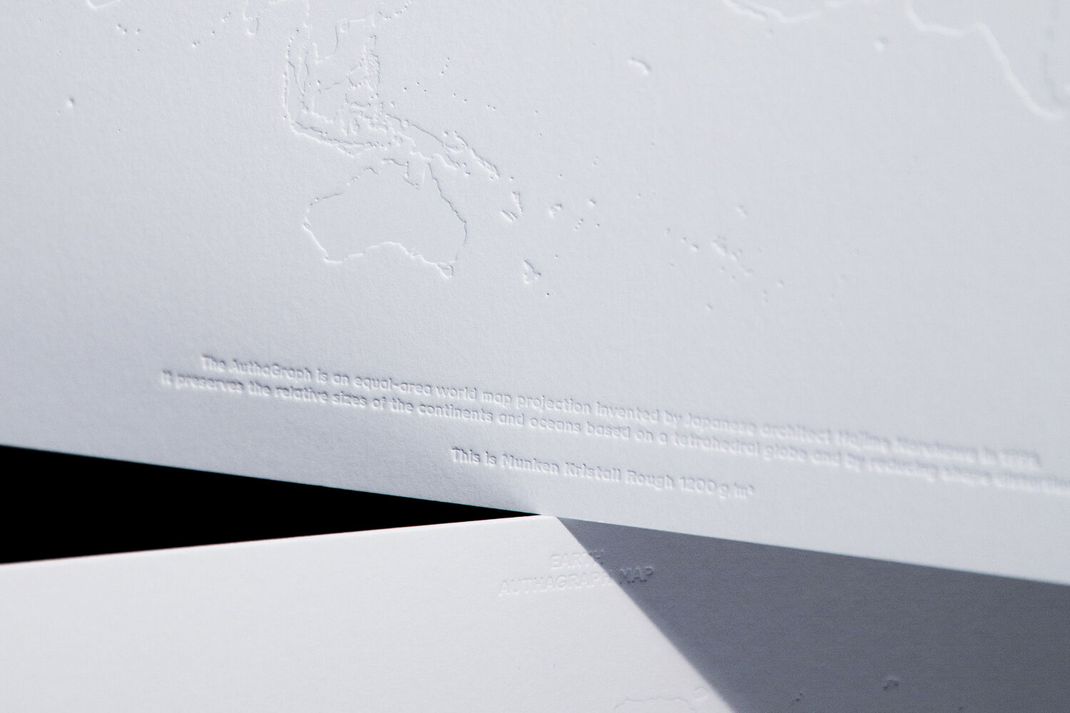 Nahaufnahme von einem dicken Papier, in das eine Weltkarte geprägt ist.