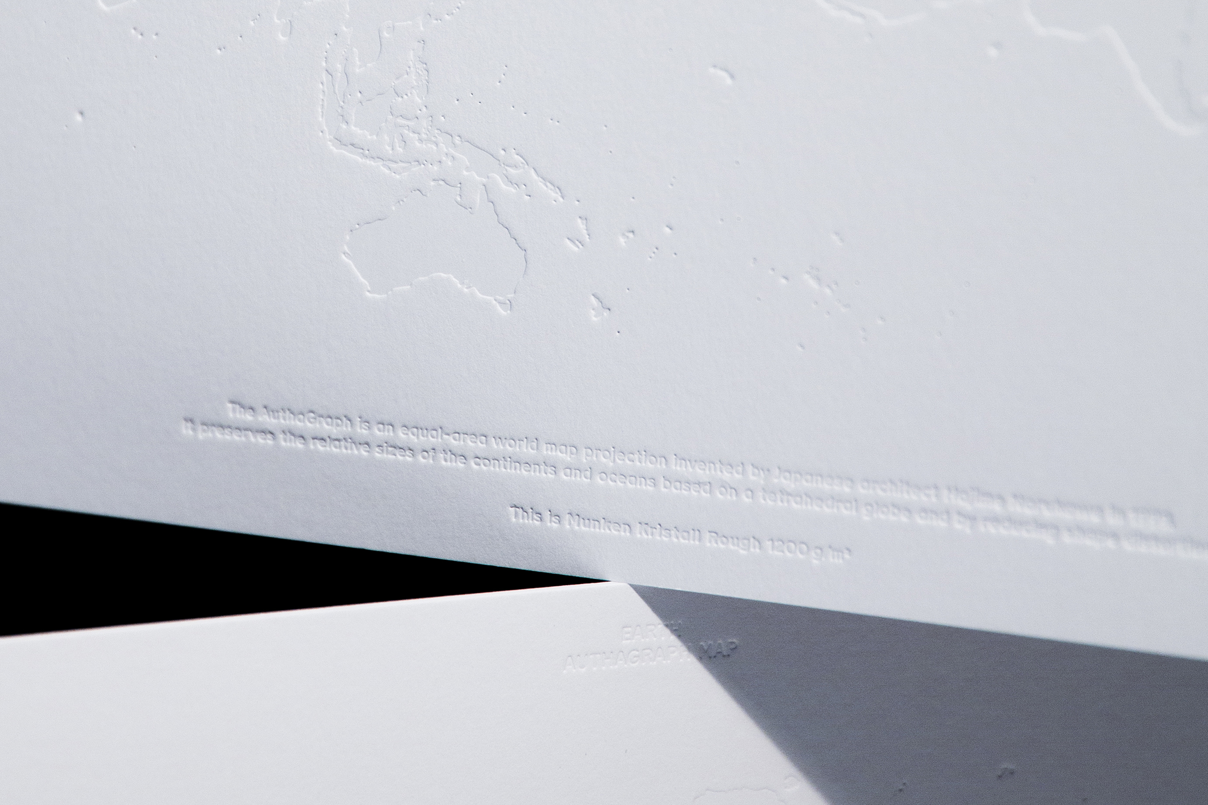 Nahaufnahme von einem dicken Papier, in das eine Weltkarte geprägt ist.