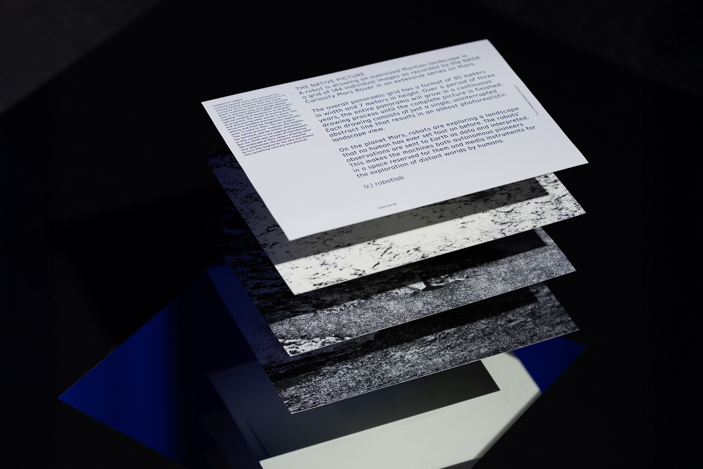 Vier Karten liegen übereinander. Auf der obersten steht ein Text, die drei unteren zeigen eine Zeichnung der Mars-Oberfläche.