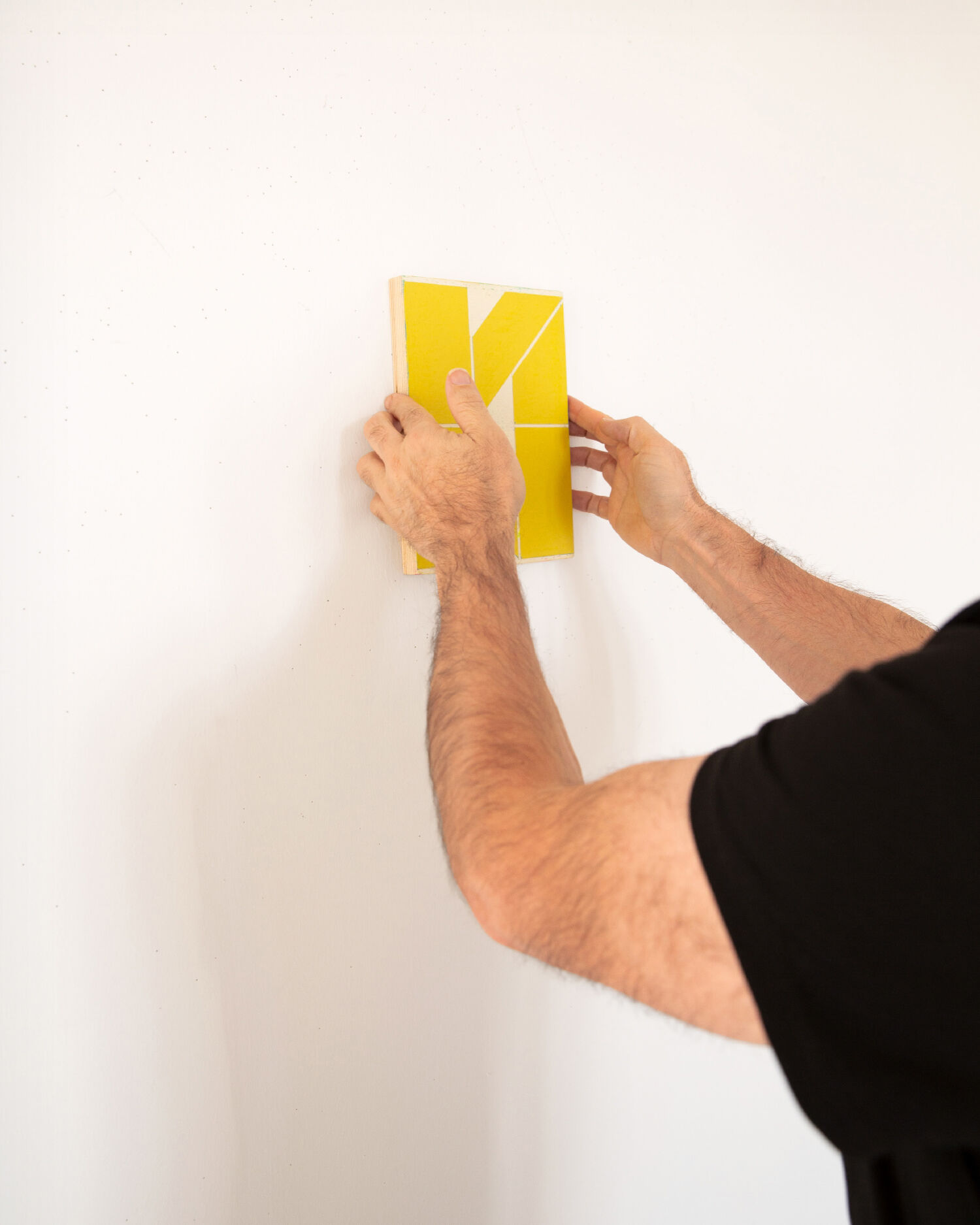 Yellow fabric sample is hung on a white wall.