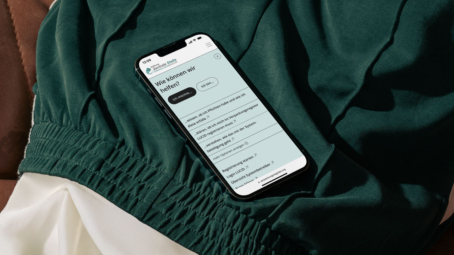 Ein Smartphone zeigt die ZSVR Startseite mit Schnelleinstieg-Funktionen. Es liegt im Schoß einer Person in dunkelgrüner Sporthose.